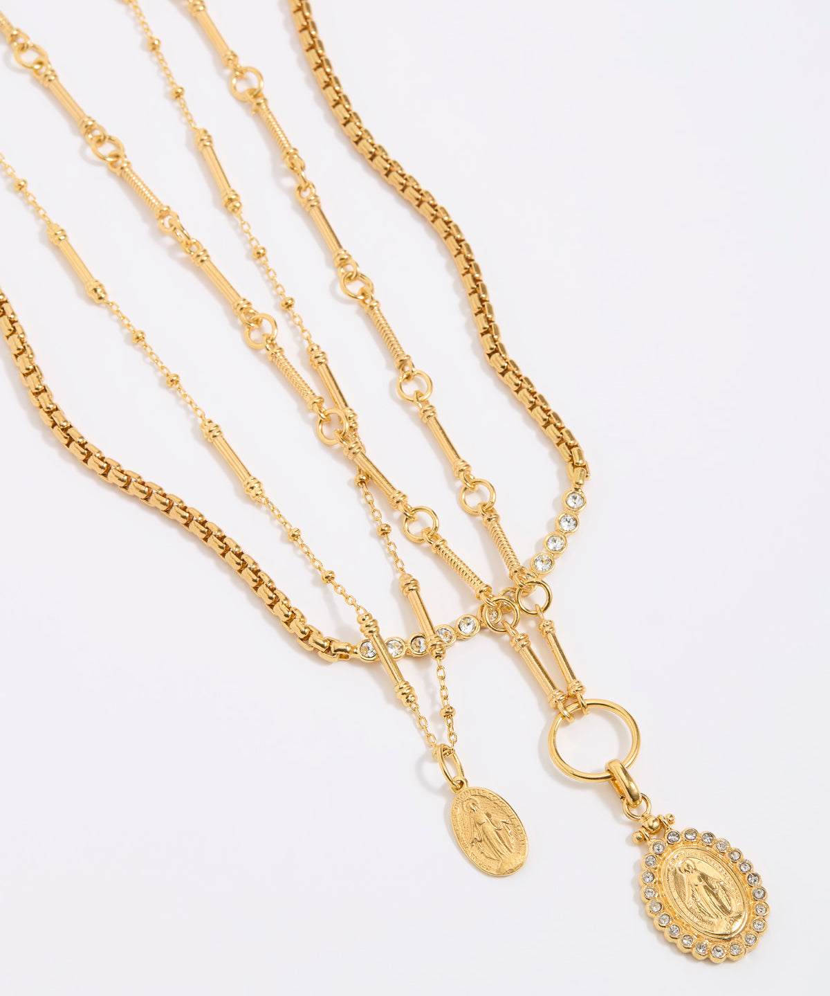 Three gold necklaces with pendants on a light gray background