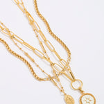 Set of gold necklaces with various links and pendants on a light gray background