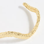 close up of textured curved gold bracelet cuff
