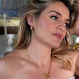 Lady wearing pendant charm necklace and gold ridged earrings