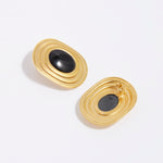 product shot of oversized gold plated silver stud earrings with oval black onyx centre