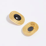 product shot of oversized gold plated silver stud earrings with oval black onyx centre