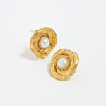 close up image shot of round gold textured earrings with centre pearl on a white back ground