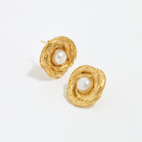 close up image shot of round gold textured earrings with centre pearl on a white back ground