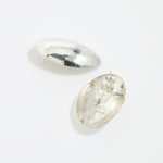 close up reverse product shot of oversized textured silver oval earrings on a white background