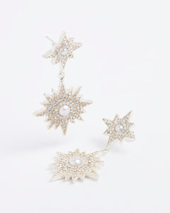 Product image of silver celestial earrings feature star burst shapes, encrusted with sparkling clear crystals and baroque pearl centres on a white background.
