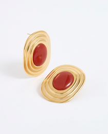 product shot of oversized gold plated silver stud earrings with oval rust centre