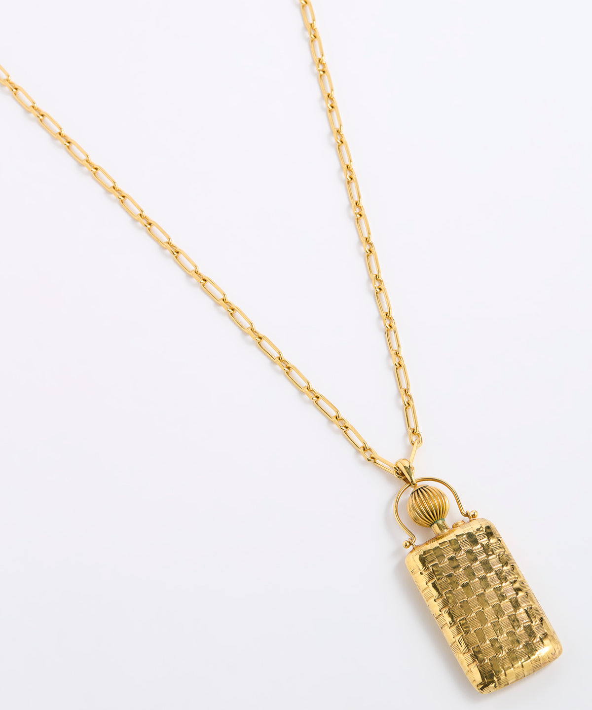A gold pendant necklace featuring a textured, rectangular handbag-shaped charm with a small gold ring detail above it, suspended from a delicate gold chain on a plain white background.