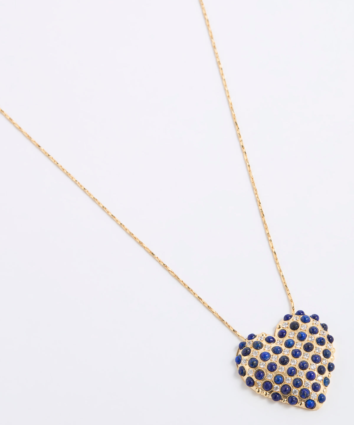 A gold chain necklace with a heart-shaped pendant covered in small dark blue lapis stones and clear sparkling crystals, set against a plain white background.