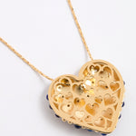 Reverse image of a gold heart-shaped pendant necklace with intricate cutout heart patterns, featuring small dark blue bead accents along the bottom edge, shown on a white background.