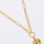 Gold heart-shaped pendant on a gold chain against a white background