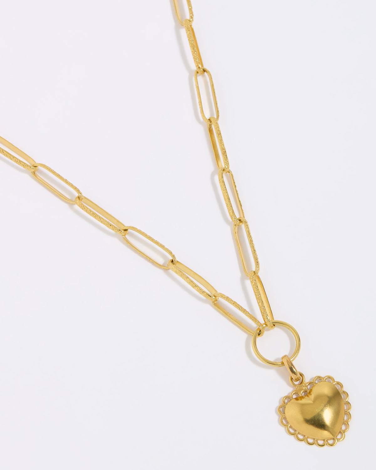 Gold heart-shaped pendant on a gold chain against a white background