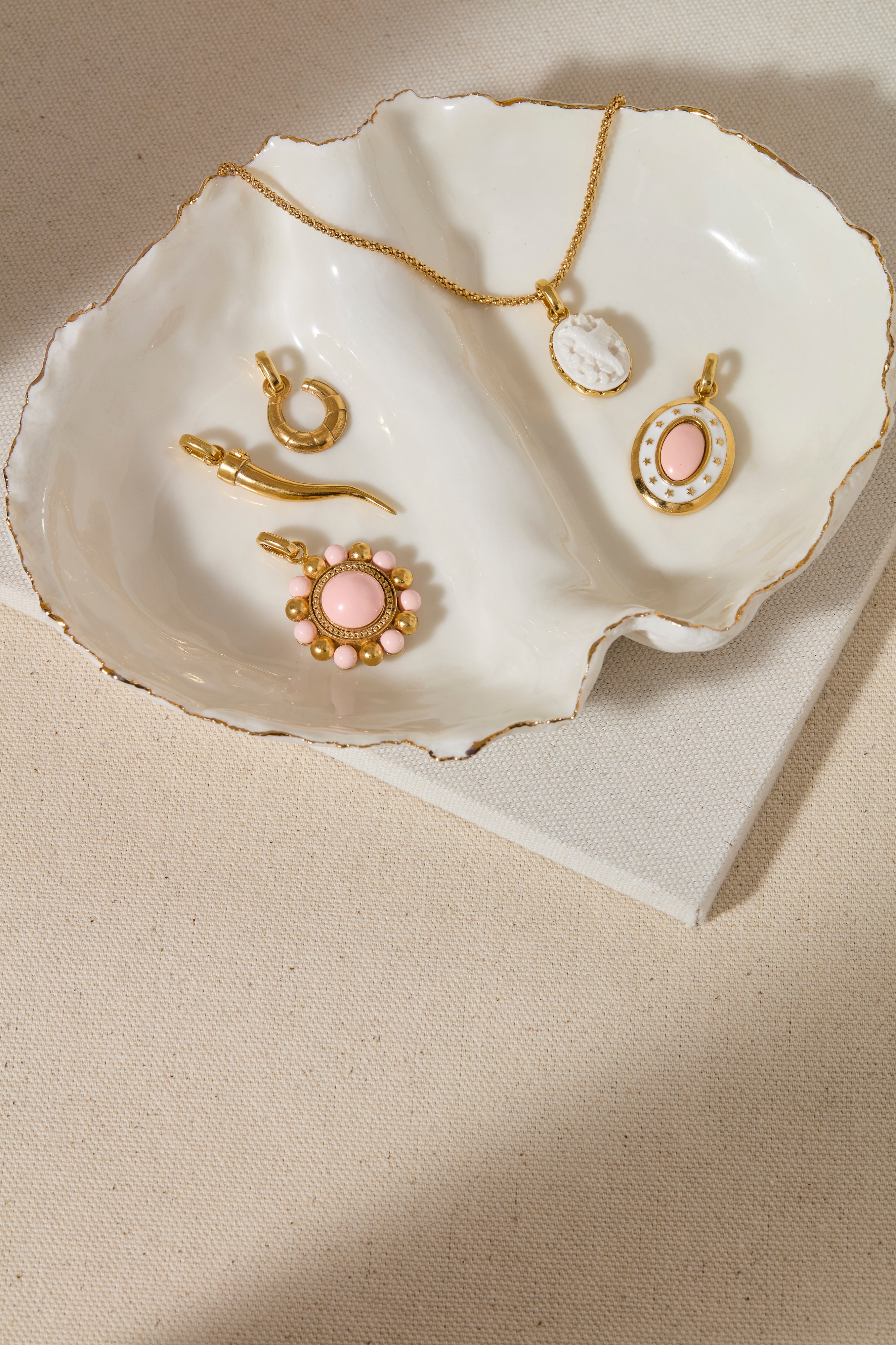 Gold coloured and pink jewelry pendants on a white shell