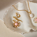 Gold coloured and pink jewelry pendants on a white shell