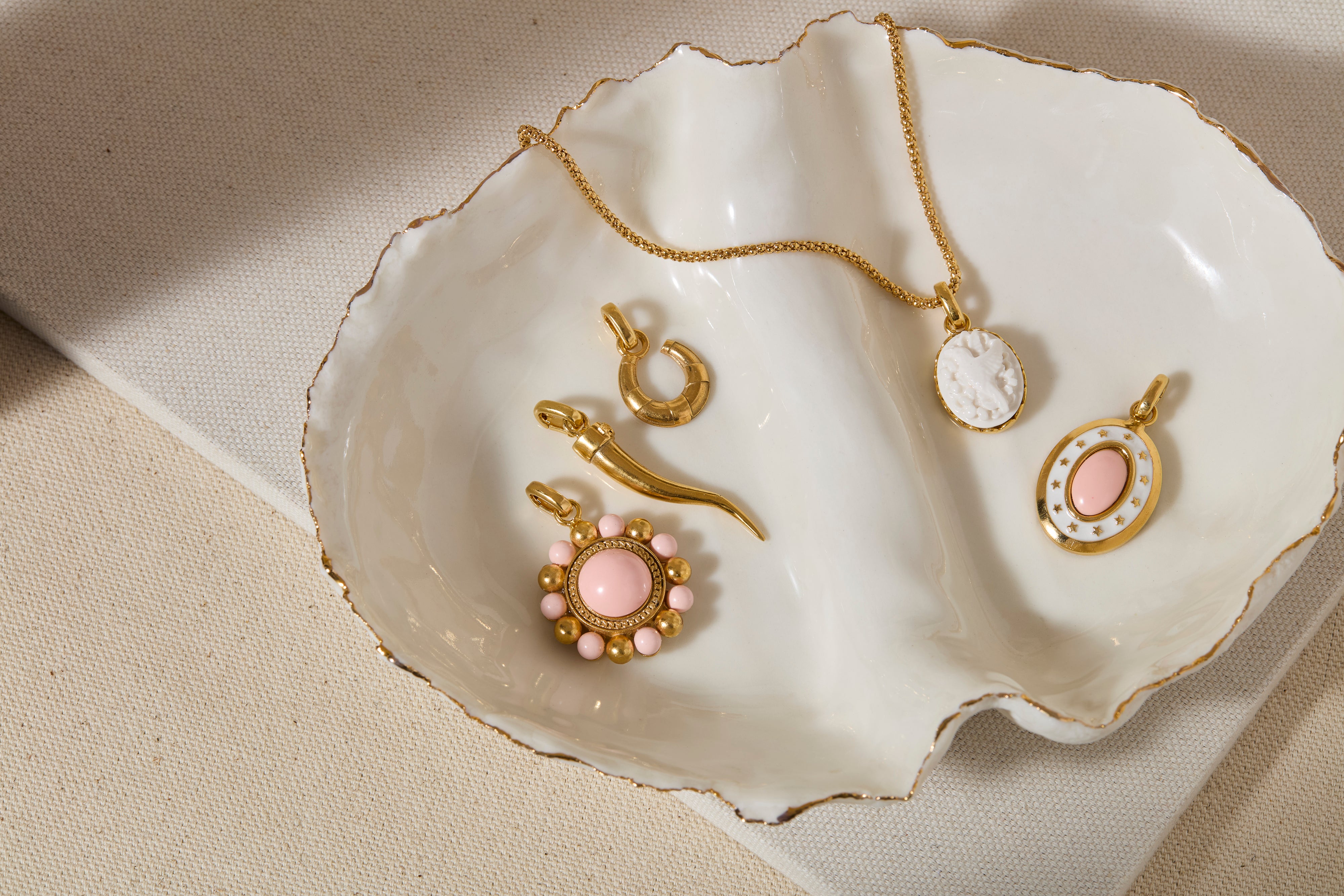 Gold coloured and pink jewelry pendants on a white shell