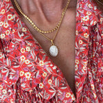 Close-up of a person wearing a red floral dress with a gold necklace.