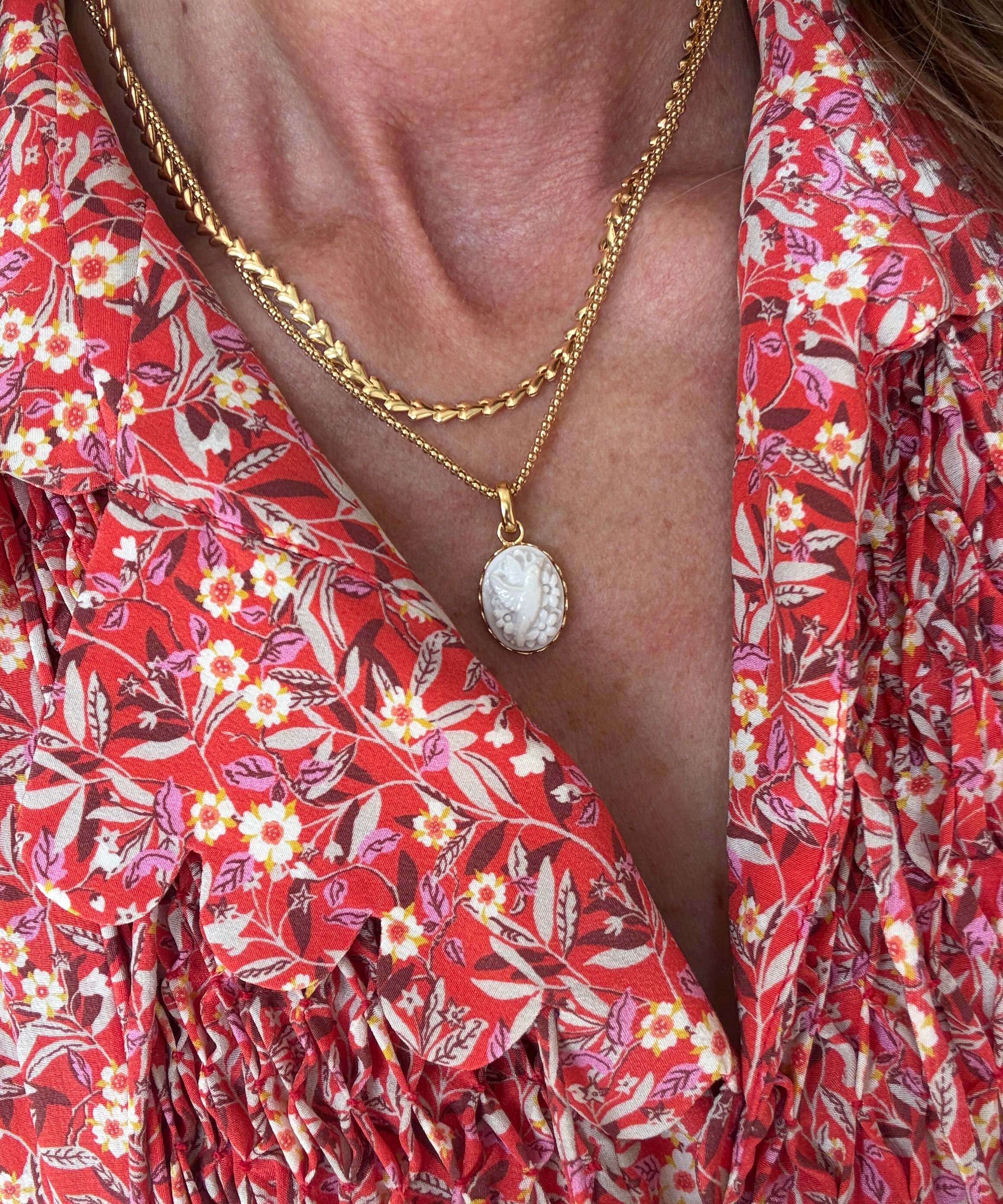 Close-up of a person wearing a red floral dress with a gold necklace.