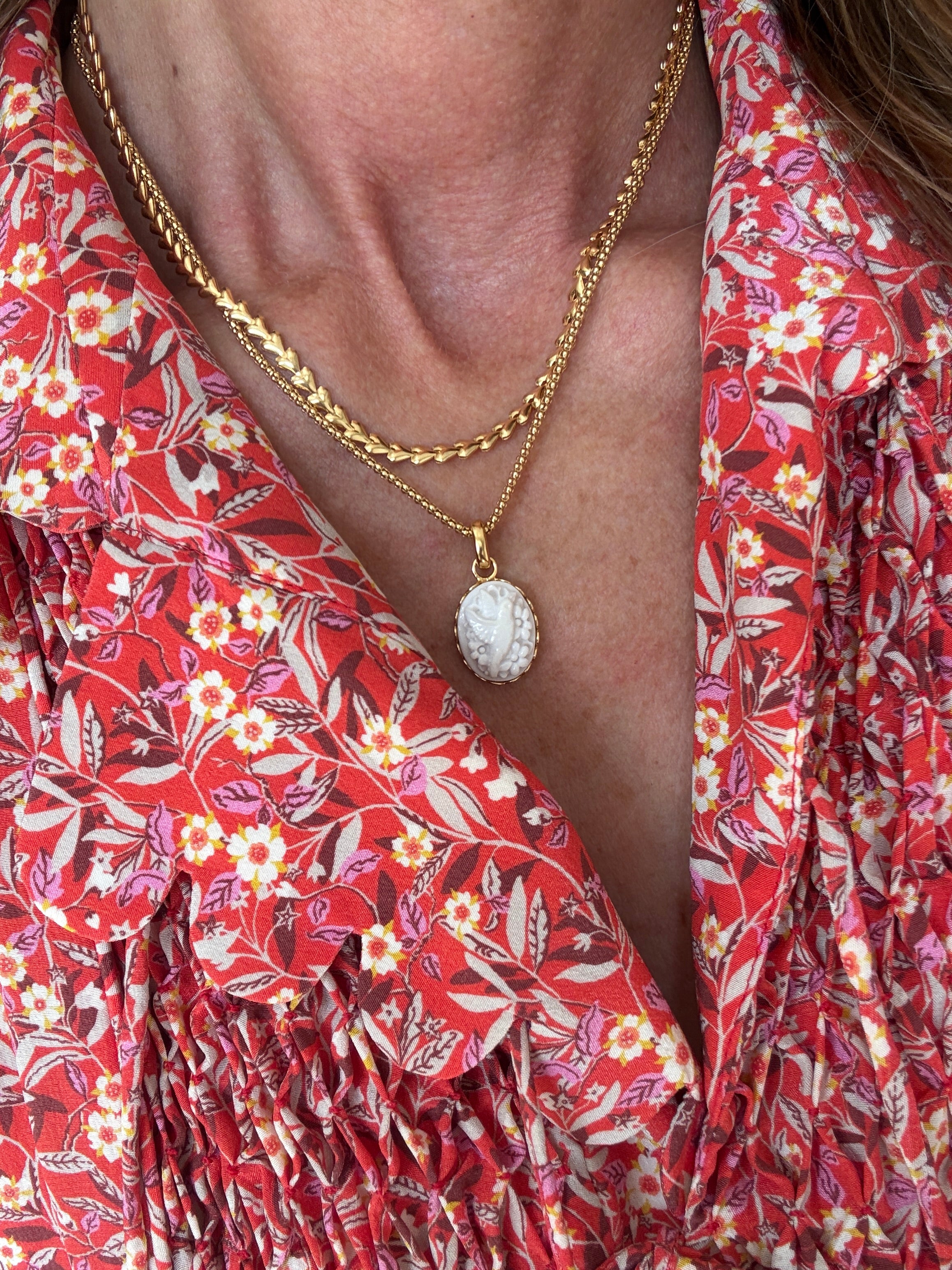 Close-up of a person wearing a red floral dress with a gold necklace.