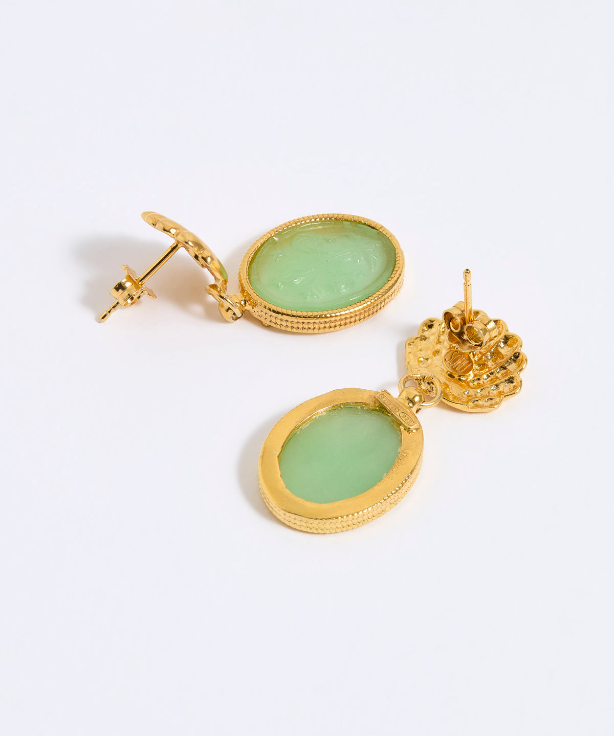 Gold earrings with green gemstones on a white background