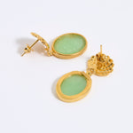Gold earrings with green gemstones on a white background