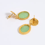 Gold earrings with green gemstones on a white background