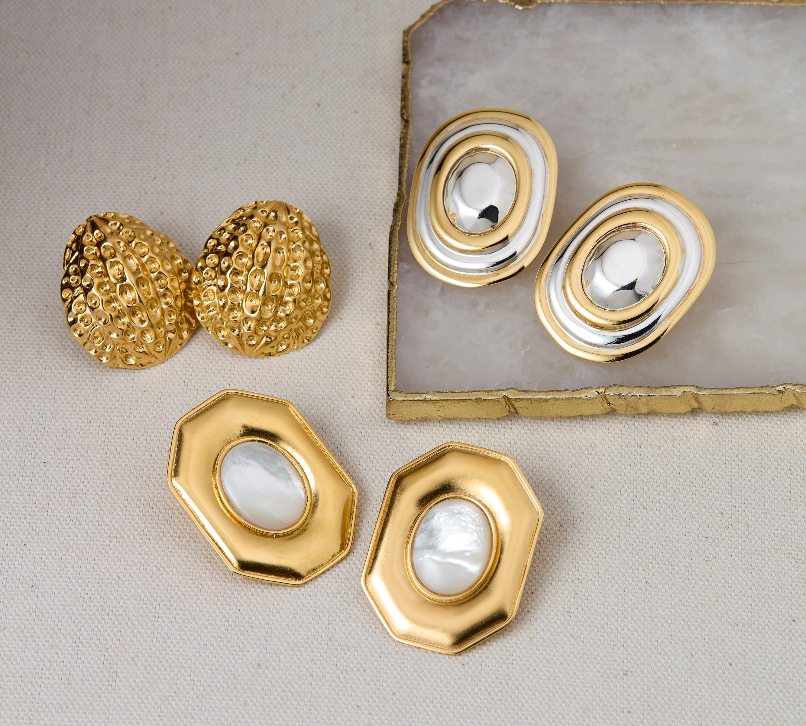 Gold and silver jewelry set on a light gray surface