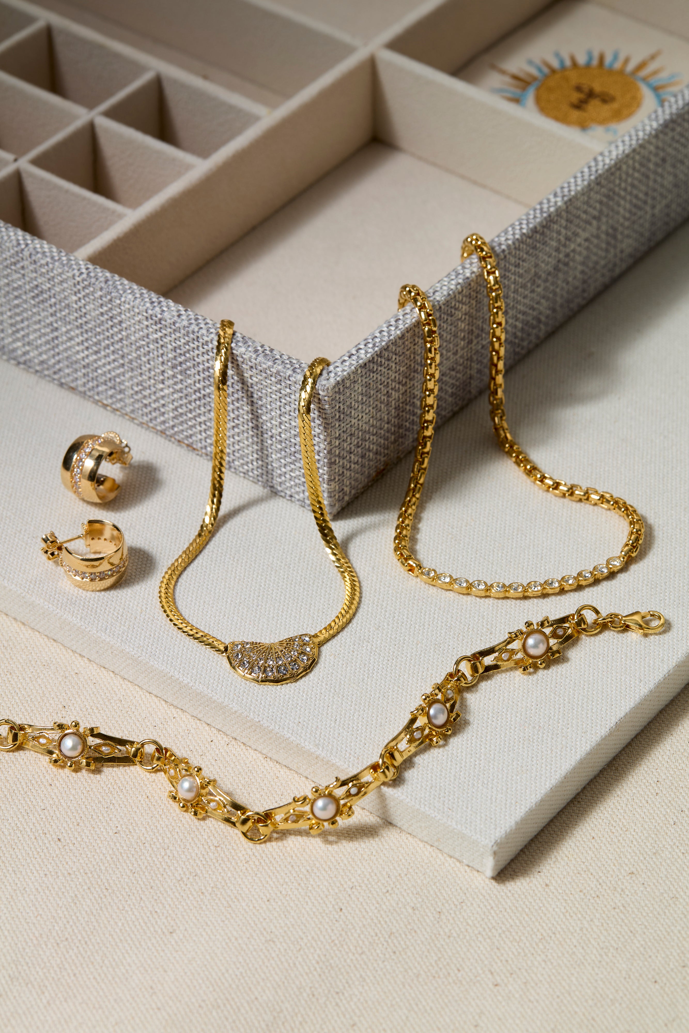 Gold jewelry set including necklace, bracelet, and earrings on a textured surface.