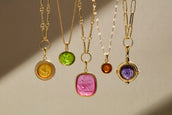 Set of gold necklaces with colorful gemstone pendants on a neutral background