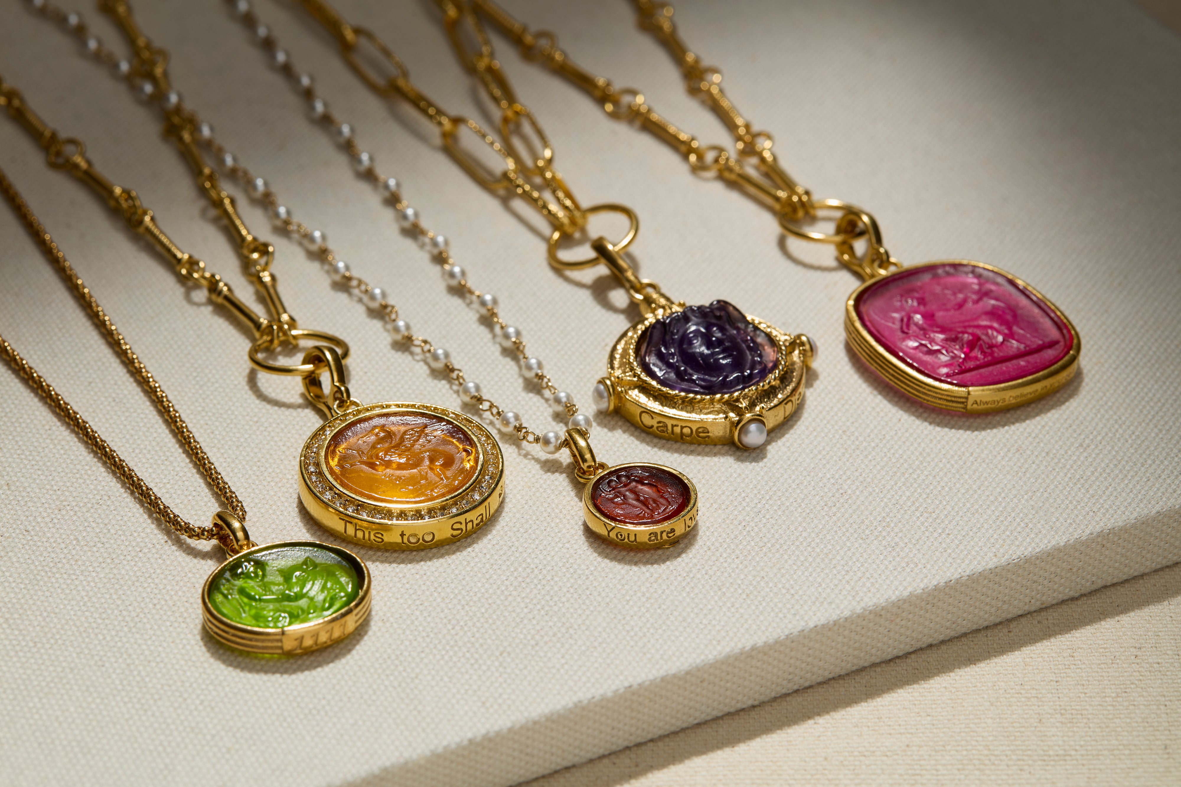 Gold necklaces with colorful gemstone pendants on a light background