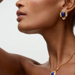 Side view of model shot of gold earrings featuring lapis central stone and embellished with pearl accents on a white background and gold necklace