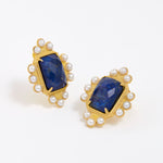 Close up product shot of gold earrings featuring lapis central stone and embellished with pearl accents on a white background
