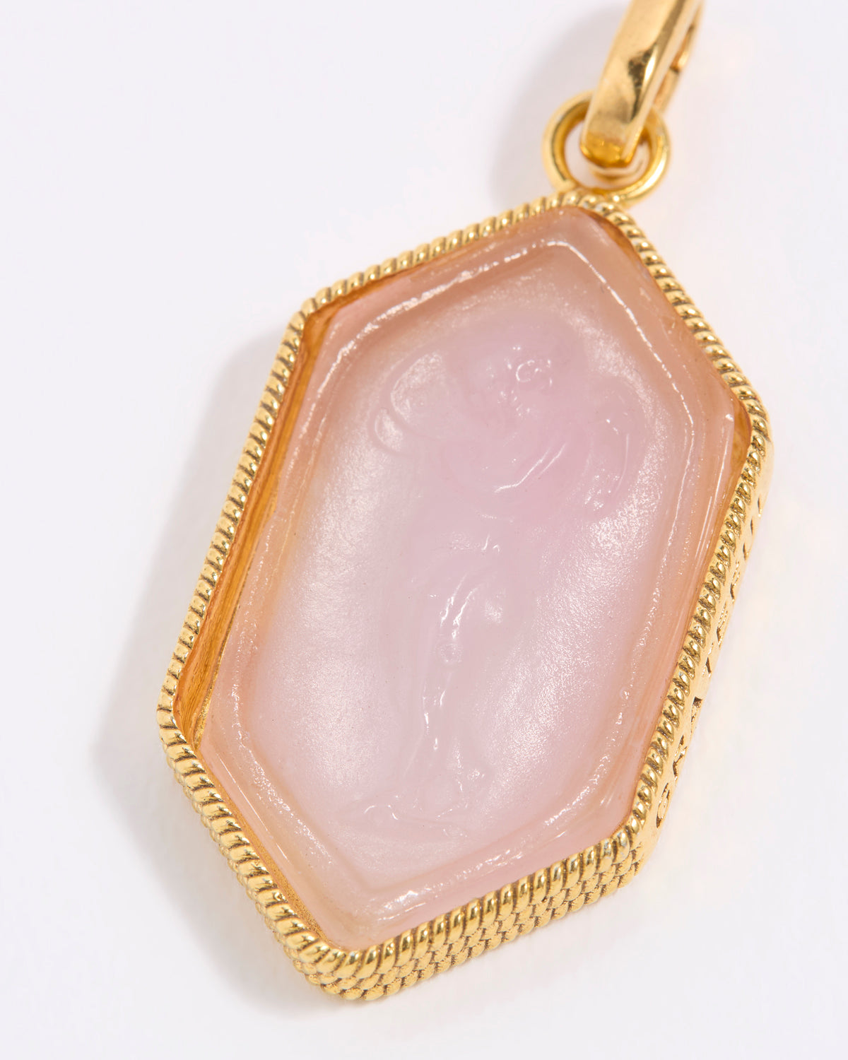 Pink stone pendant featuring cut out of cherub, with gold frame on a white background