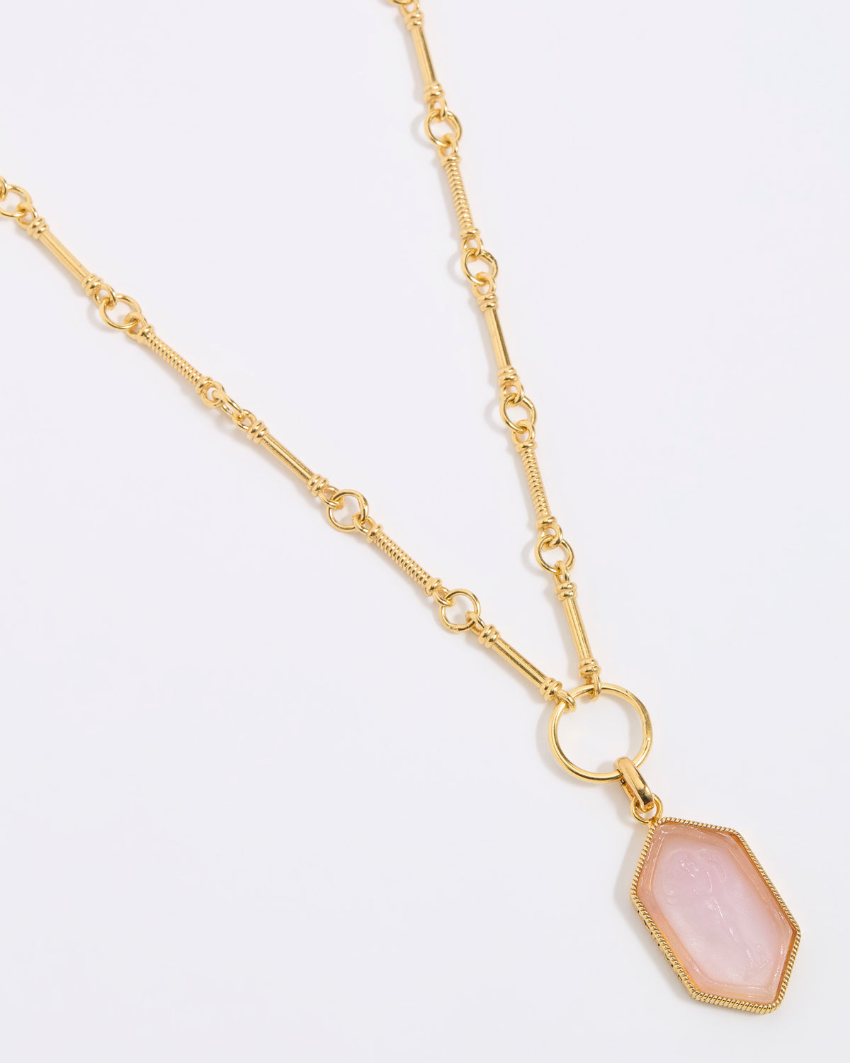 Gold necklace with a pink pendant on a light gray background