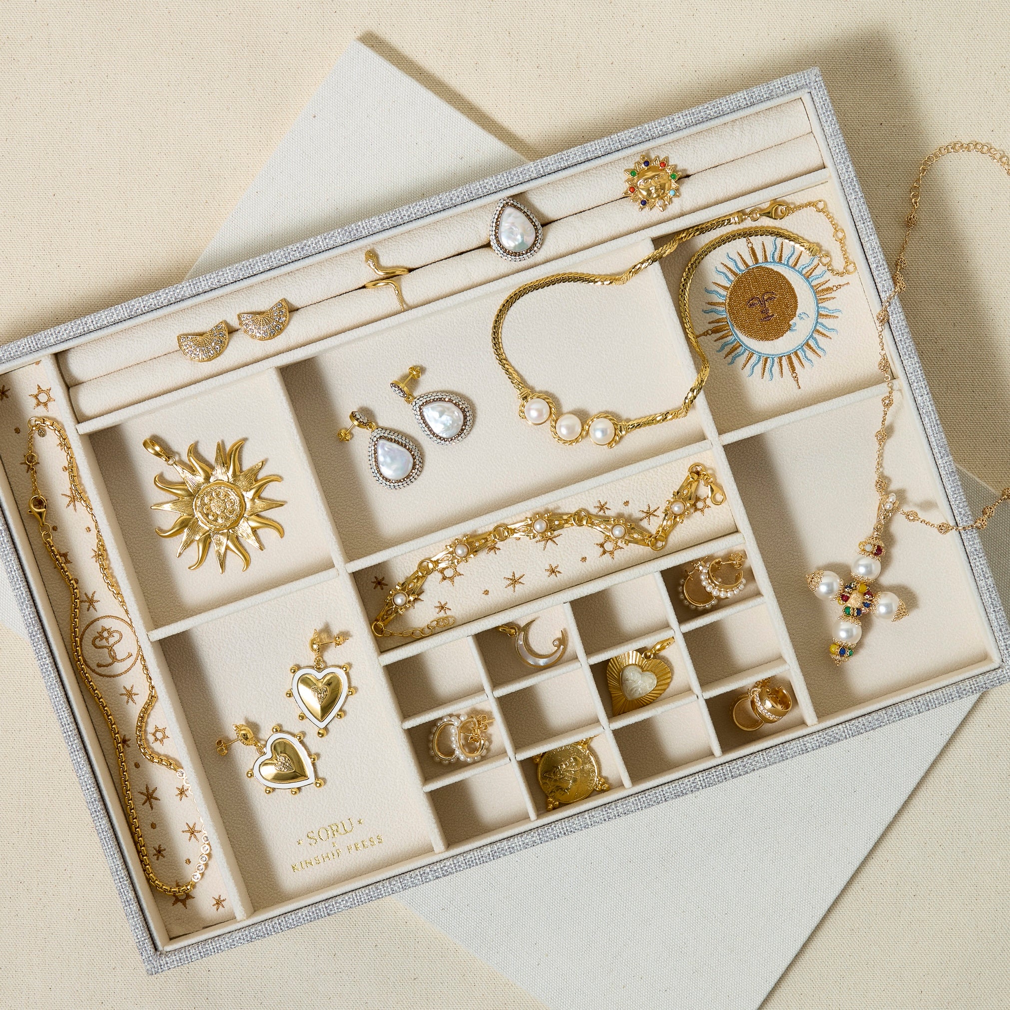 Jewellery storage box with layered jewellery on a cream. background