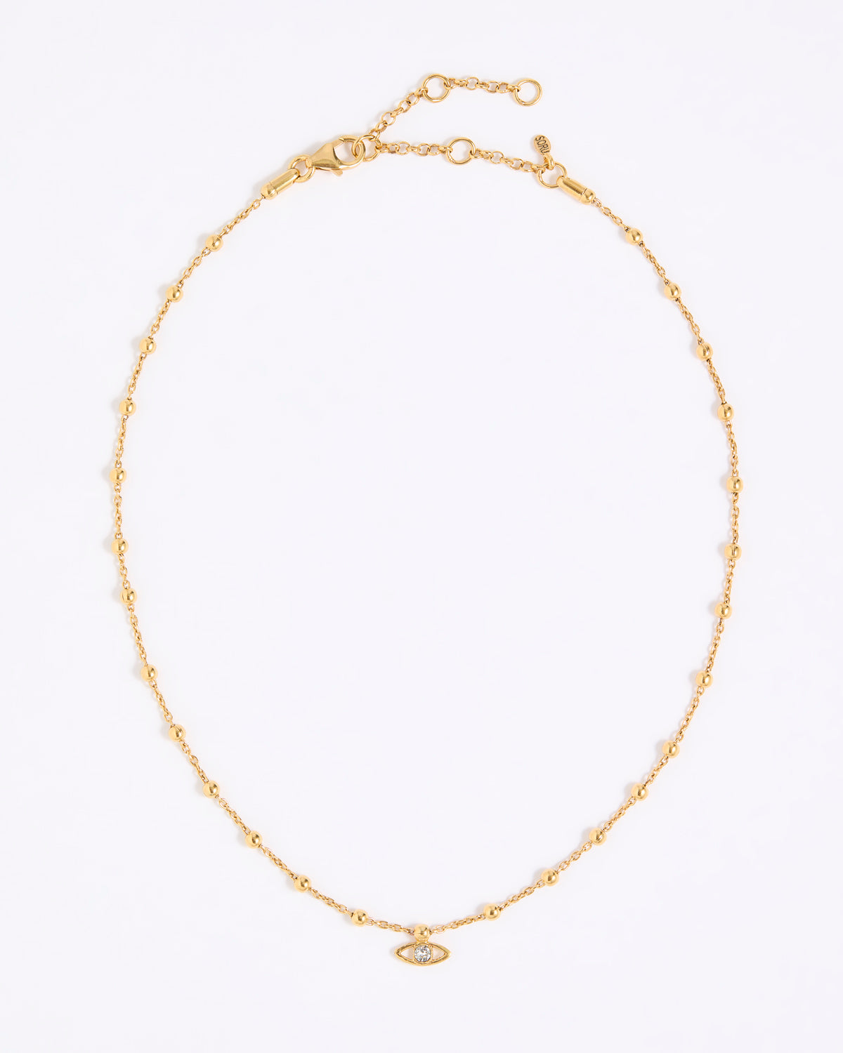 Gold coloured necklace with a small eye pendant on a white background