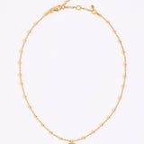 Gold coloured necklace with a small eye pendant on a white background