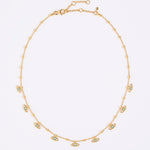 Gold necklace with small eye-shaped charms on a light gray background