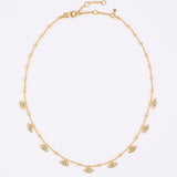 Gold necklace with small eye-shaped charms on a light gray background