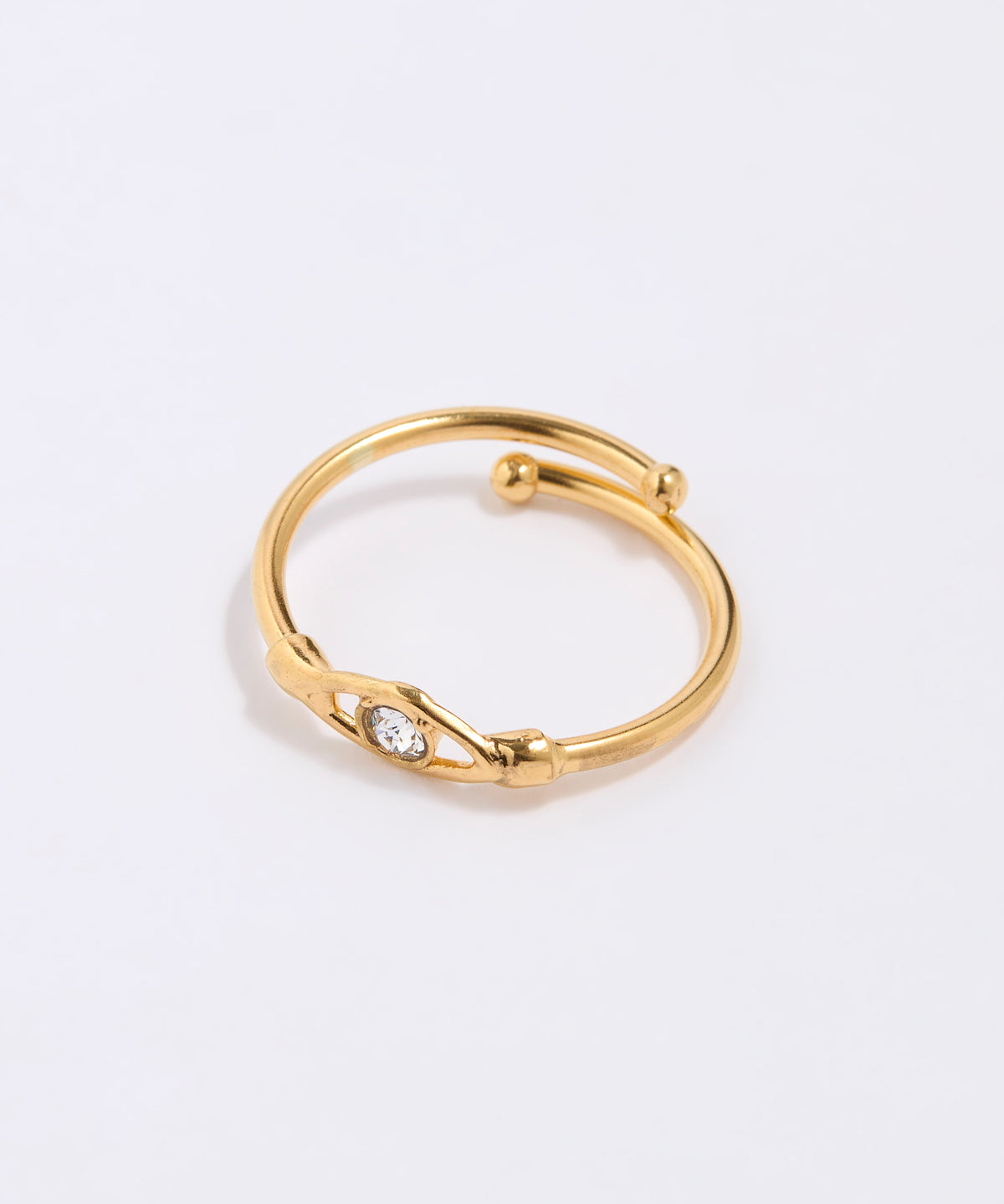 Gold coloured ring with a clear crystal at the centre of an evil eye on a light gray background