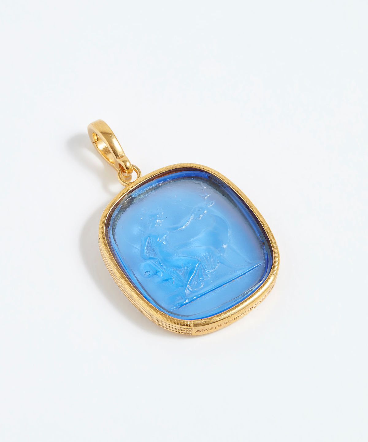 Gold pendant with a blue stone on a white background