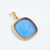 Gold pendant with a blue stone on a white background