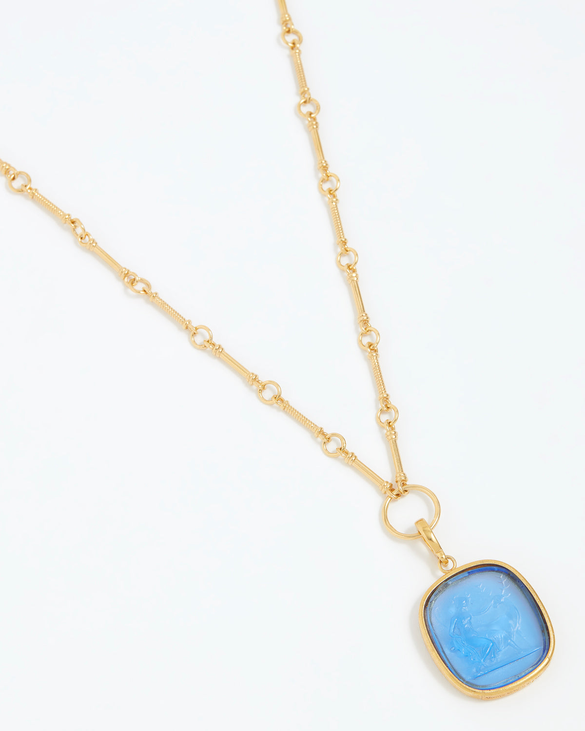 Gold necklace with a blue pendant on a white background