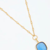 Gold necklace with a blue pendant on a white background