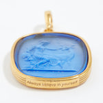 Gold pendant with blue stone and 'Always believe in yourself' engraving on a white background