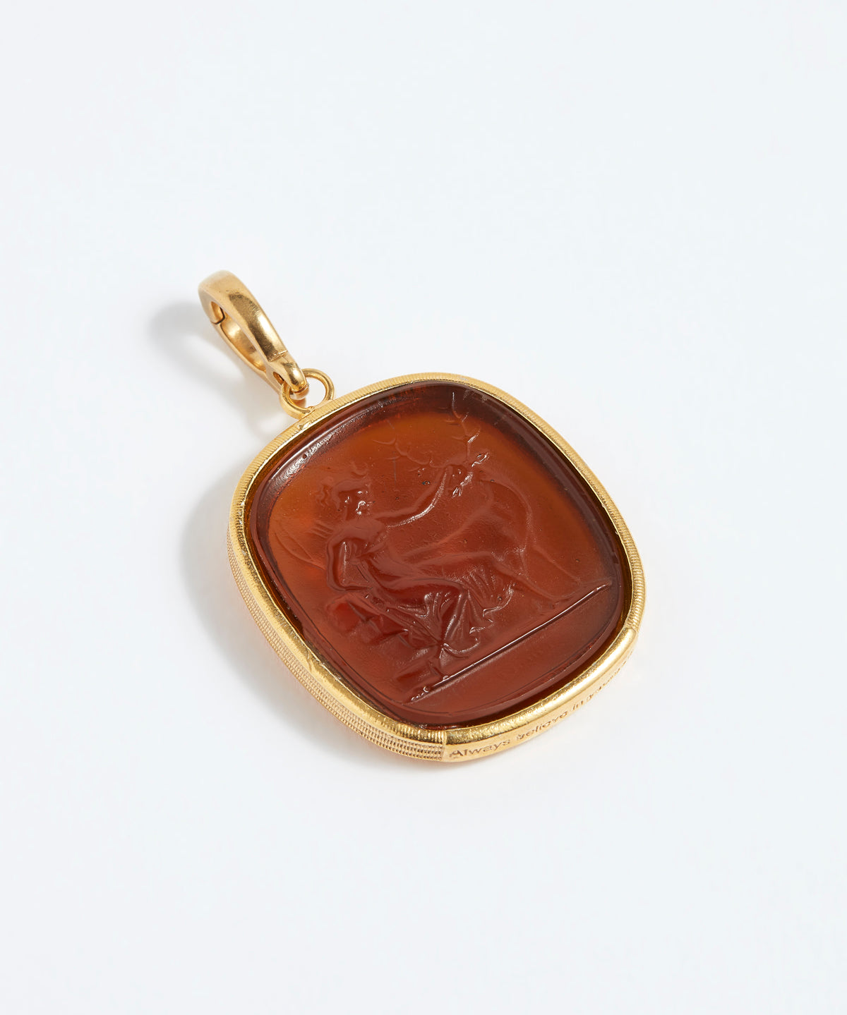 Gold pendant with a brown stone featuring an engraved design on a white background