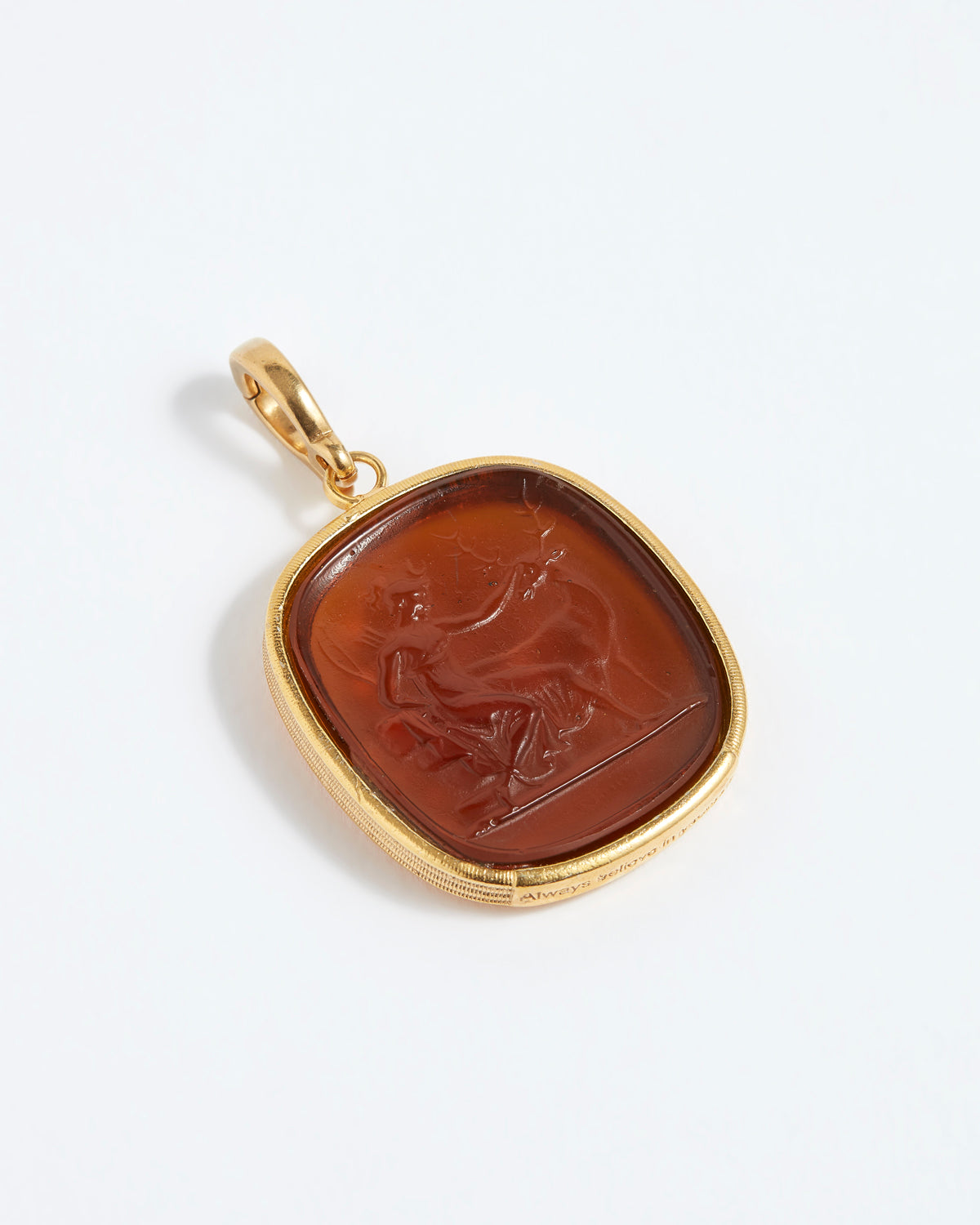 Gold pendant with a brown stone featuring an engraved design on a white background