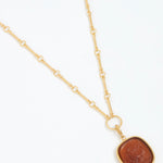 Gold necklace with a brown pendant on a white background