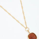 Gold necklace with a brown pendant on a white background