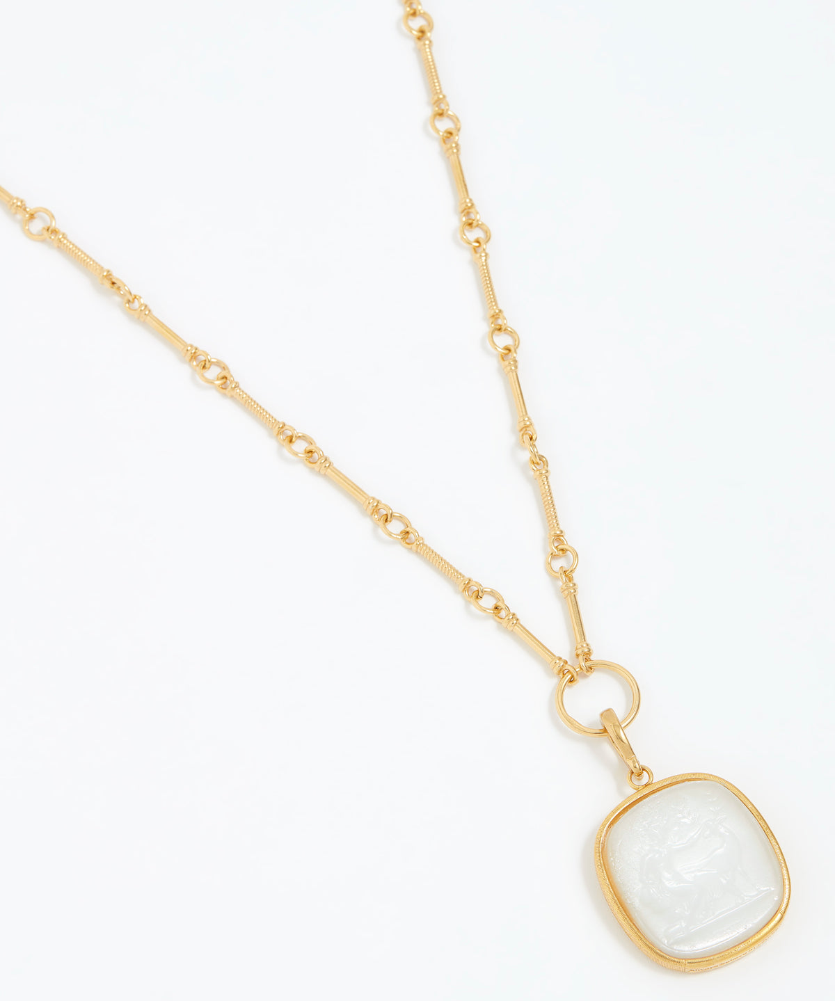 Gold necklace with a white pendant on a white background