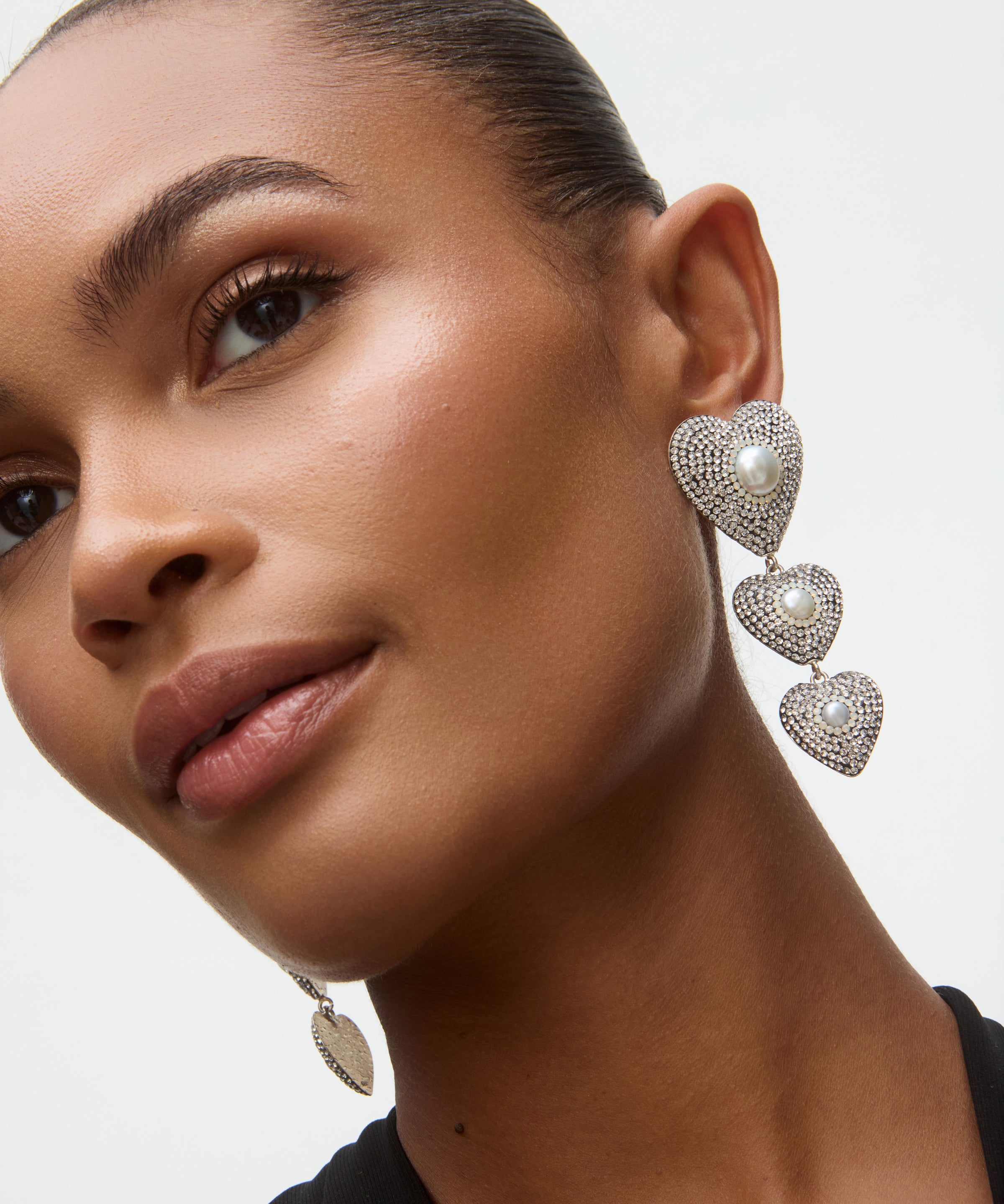 Close-up of a woman wearing heart-shaped earrings with a neutral background